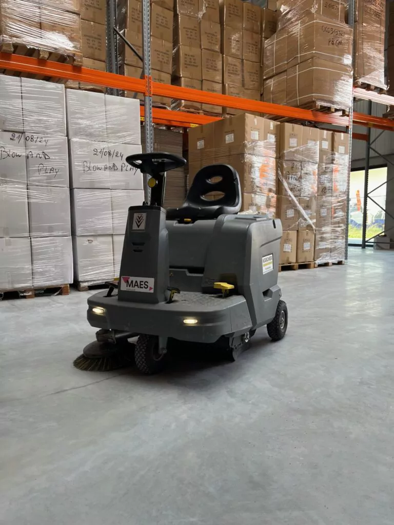 Three professional cleaners in green and red overalls working in a modern kitchen, mopping the floor, and cleaning high walls and windows.